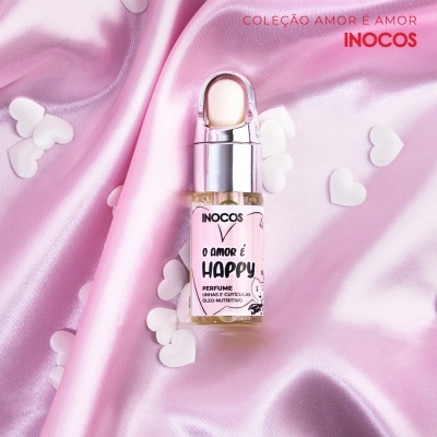 Frasco pequeno de perfume O AMOR É HAPPY sobre tecido rosa com corações brancos