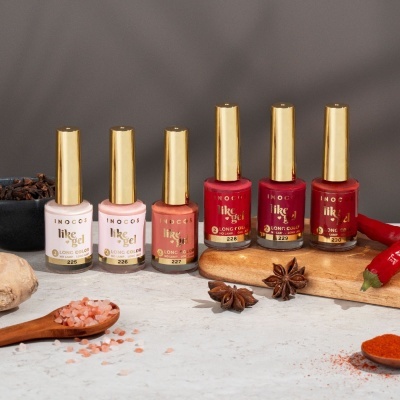 Seis frascos de verniz de unhas Inocos em cores variadas sobre mesa com especiarias.