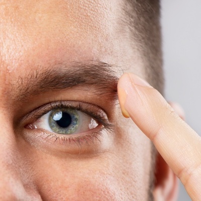 Homem a aplicar disco de lentilha cosmética transparente na testa