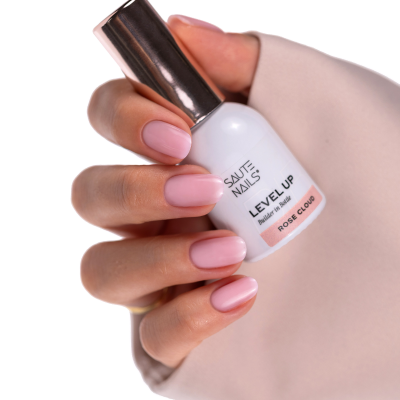 Frasco de verniz branco com tampa prateada segurado por mãos com unhas cor rosa claro
