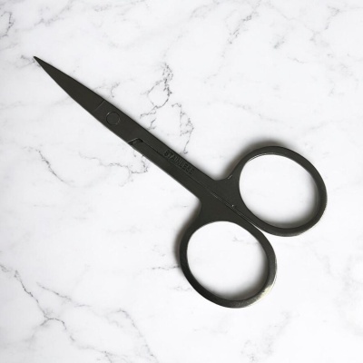 Tesoura preta pequena sobre superfície branca com padrão de mármore