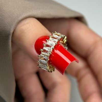 Anel dourado com pedras retangulares e unhas vermelhas