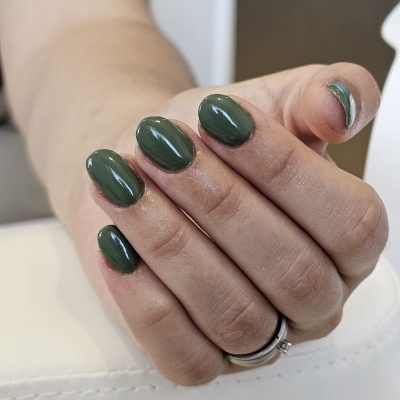 Mãos femininas com unhas verdes e anéis prateados