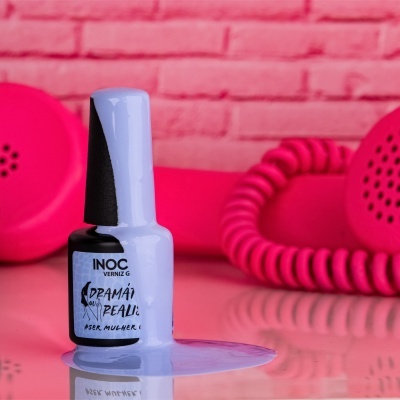 Frasco de verniz azul claro derramado com telefone vintage rosa ao fundo