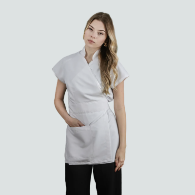 Mulher com túnica branca de manga curta e bolso frontal sobre fundo cinzento