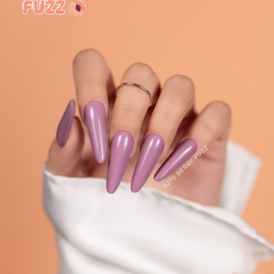 Unha artificial lilás brilhante com texto S270 BERRY FUZZ, mão com anel, fundo pêssego