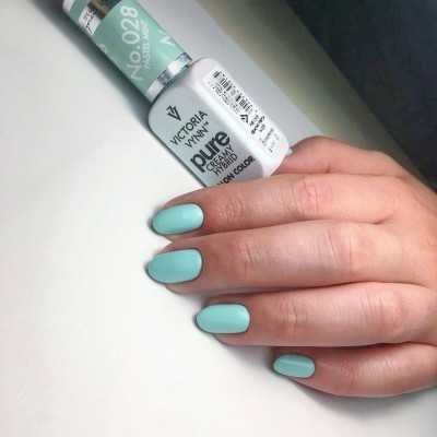Unhas pintadas com esmalte verde menta pastel Victoria Vynn e frasco do produto ao fundo