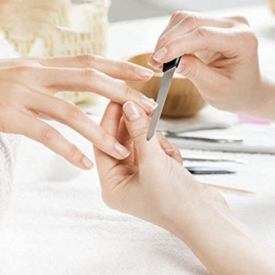 Mãos a fazer manicure com lima de unhas