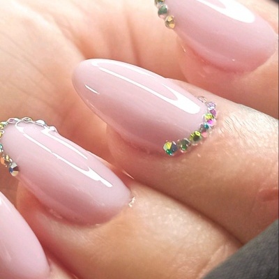 Unhas artificiais rosa claro com pedras decorativas nas pontas