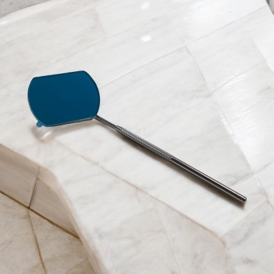 Espelho de mão com cabo metálico e espelho azul numa superfície de mármore branco