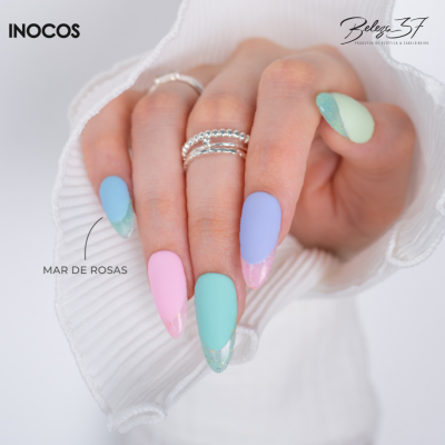 Mãos com unhas coloridas pastel decoradas e anéis prateados