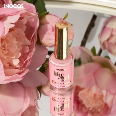Frasco de verniz para unhas cor-de-rosa com tampa dourada junto a flores cor-de-rosa refletido num espelho