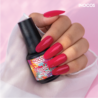 Mão com unhas pintadas de verniz gel rosa segurando frasco de verniz INOCOS