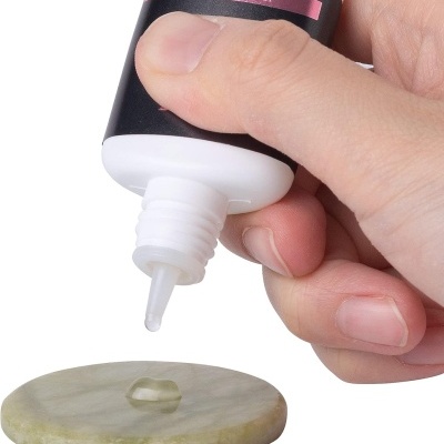 Mão a segurar tubo a derramar líquido sobre disco redondo