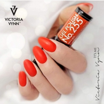Mão com unhas vermelhas e frasco de verniz VICTORIA VYNN