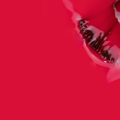 Frasco de verniz de unhas vermelho com pincel, derramado, sobre fundo vermelho