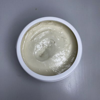 Recipiente branco aberto com creme de textura densa bege claro