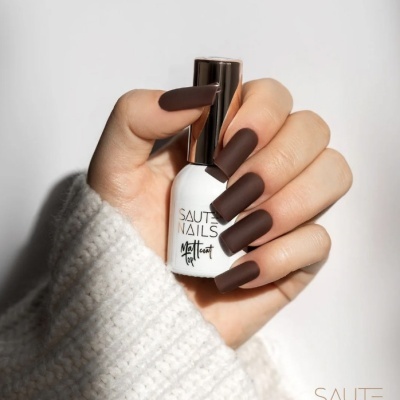 Verniz de unhas branco com tampa dourada na mão com unhas castanhas mate