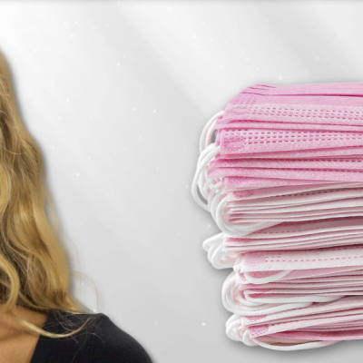 Máscaras cirúrgicas rosas empilhadas ao lado de mulher com máscara rosa