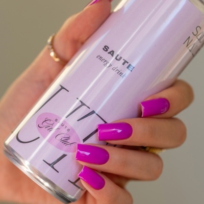 Mão com unhas roxas segurando uma lata lilás de bebida energética.