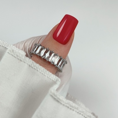 Anel prateado com pedras retangulares e unha vermelha em fundo branco