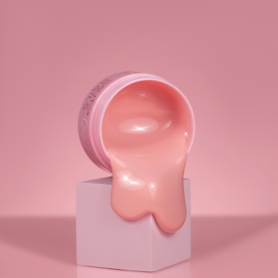 Frasco aberto de verniz rosa claro a escorrer num cubo rosa claro