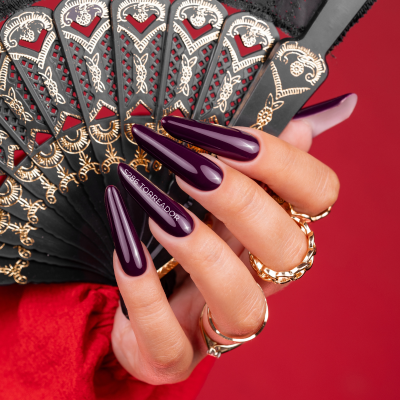 Mão com unhas roxas longas segurando leque preto decorado