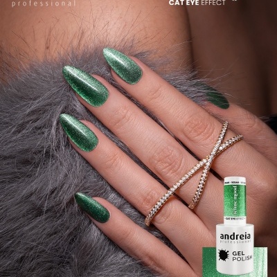 Unhas em gel verde metálico com efeito cat eye e anel dourado sobre fundo cinzento felpudo