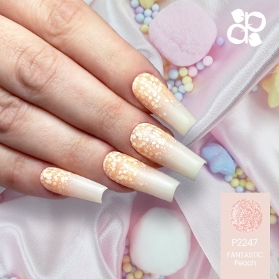 Unhas alongadas branco e pêssego com brilhos sobre tecido rosa e confeitos coloridos