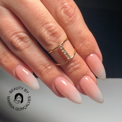 Unhas amêndoa rosa claro para branco com anel dourado e cristais em fundo escuro