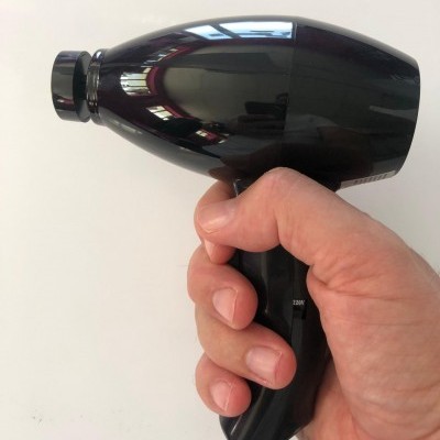 Secador de cabelo preto com acabamento brilhante segurado por uma mão