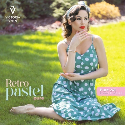 Mulher vestindo vestido verde-pastel de bolinhas brancas sentada na relva com batom vermelho