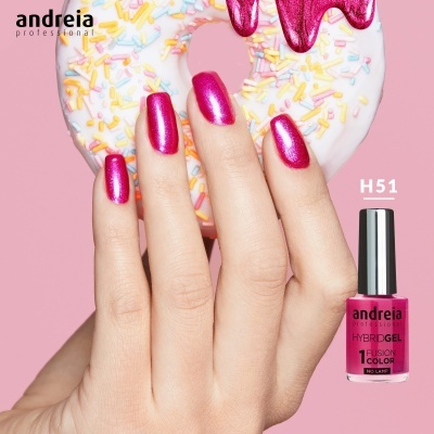 Mão com unhas rosa metálico segurando donut branco com confeitos e frasco de verniz