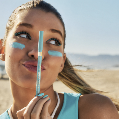 Mulher ao ar livre segurando lápis de maquilhagem azul