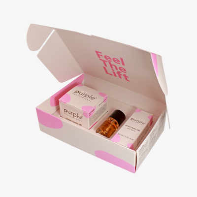 Caixa de produto de cuidados de pele branca e rosa aberta com produtos purple professionals e frasco âmbar