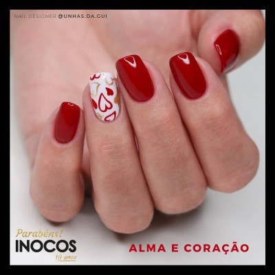Unha com verniz vermelho e decoração de corações em branco