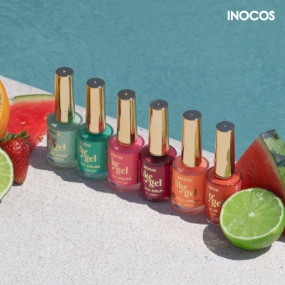 Seis frascos de verniz de unhas INOCOS coloridos ao lado de frutas junto a piscina