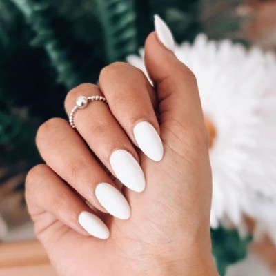 Mão com unhas postiças brancas e anel prateado