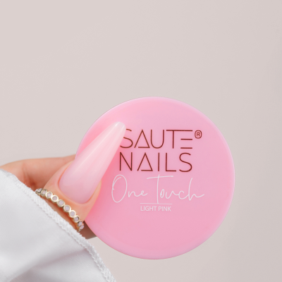 Frasco rosa claro de cosmético para unhas segurado por mão com unha longa e rosa clara.