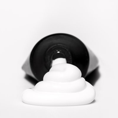 Tubo preto com creme branco espiralado à frente e logo SAUTE NAILS