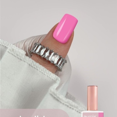 Unha com verniz gel rosa vibrante e anel prateado com pedras, embalagem de verniz ao fundo