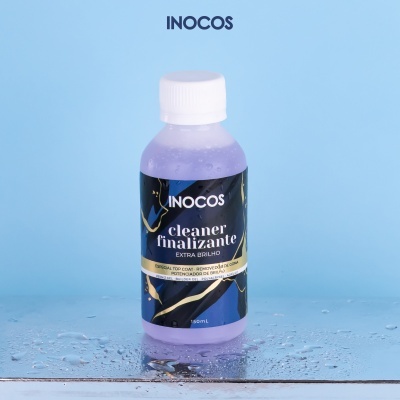 Frasco plástico roxo com rótulo preto, azul e dourado e tampa branca sobre superfície molhada