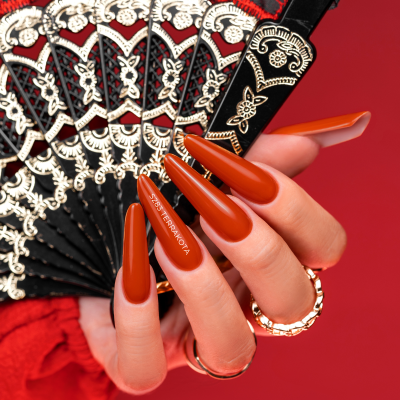 Mão com unhas castanho-avermelhado segurando leque decorativo preto e vermelho