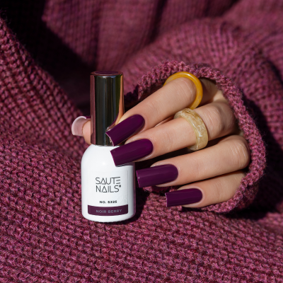 Frasco de verniz de unhas branco com tampa metálica e unhas pintadas cor berinjela