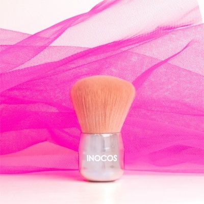 Pincel de maquilhagem INOCOS com tecido rosa ao fundo.