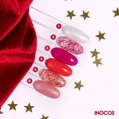 Paleta de amostras de esmaltes com diversas cores e brilhos sobre fundo branco com estrelas douradas e tecido vermelho.