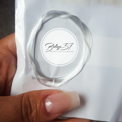 Mão segurando anel transparente fino sobre fundo branco com selo 'Beleza 37'