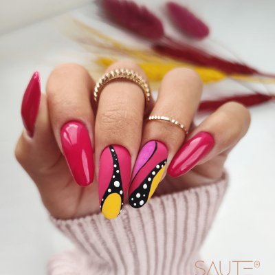 Unhas pintadas com verniz rosa e design artístico colorido com flores secas ao fundo.