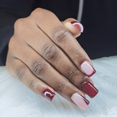 Mão com unhas decoradas vermelhas e rosa claro, formato quadrado