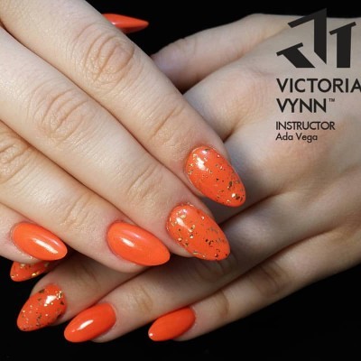 Unhas pintadas de laranja com pontos dourados